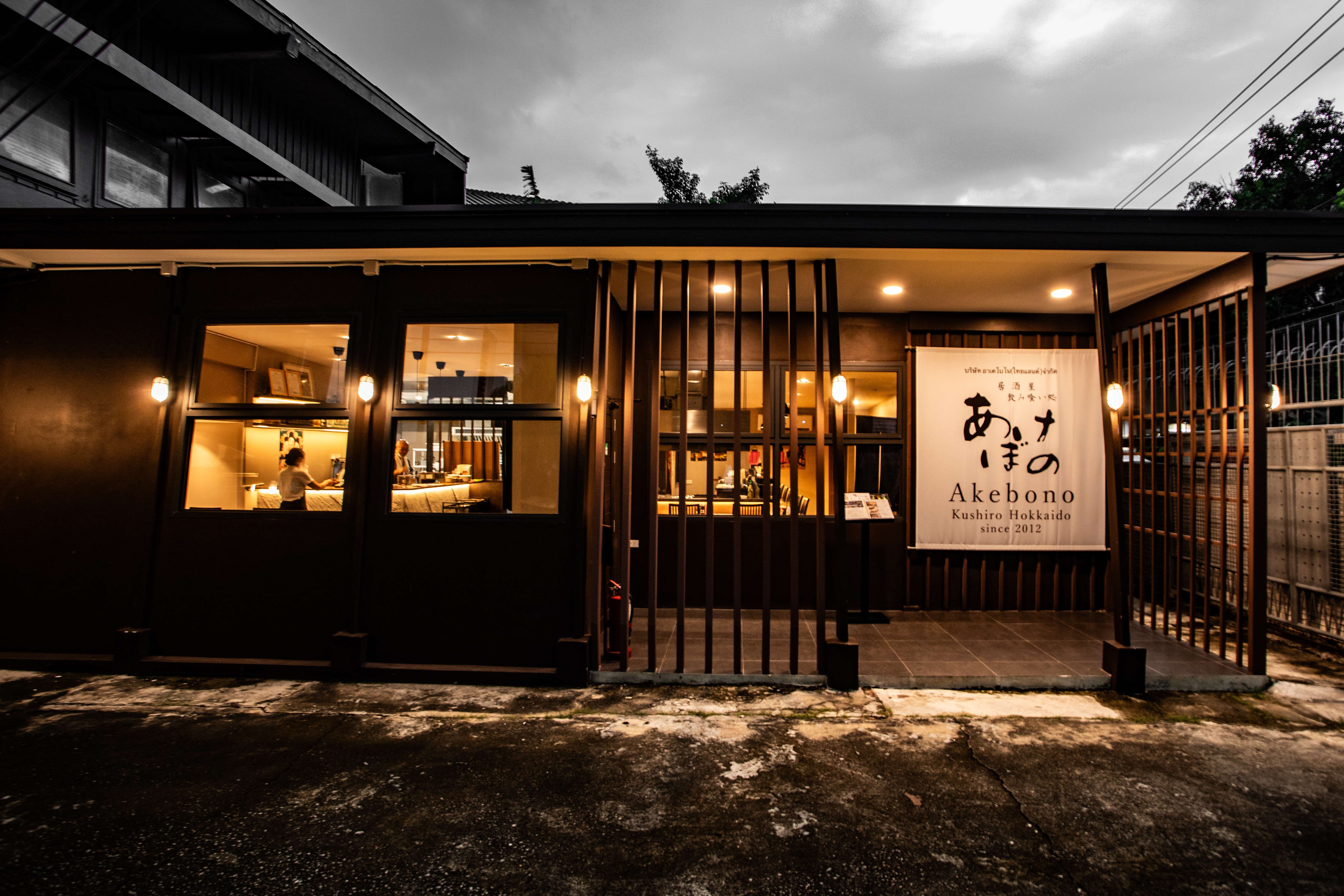 暖かな照明と「あけぼの」ののれんがあるAkebonoバンコク店の外観